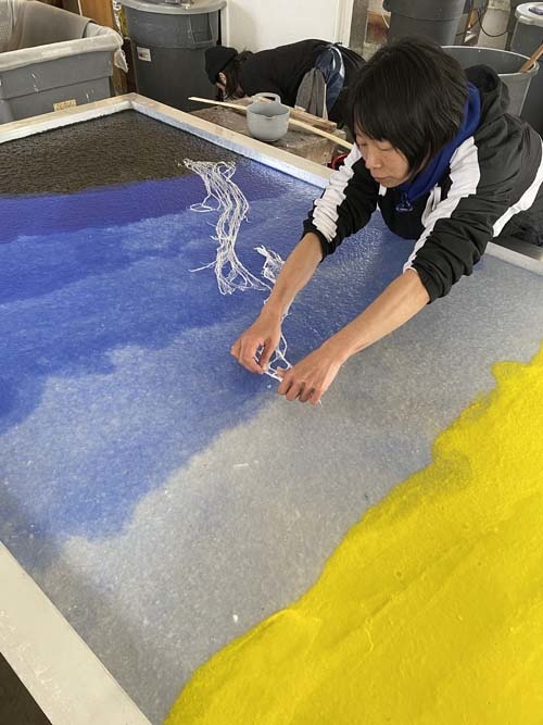 Masami Igarashi, a Japanese papermaker, adds colored pulp to a screen