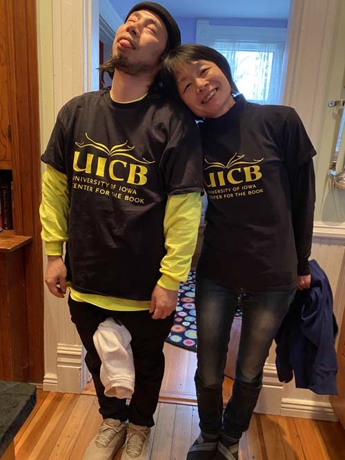 Two Japanese Papermakers wearing UICB shirts stand together looking exhausted