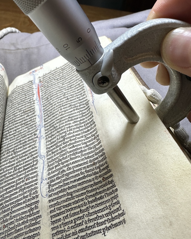 calipers measuring thickness of a parchment leaf in a medieval European manuscript