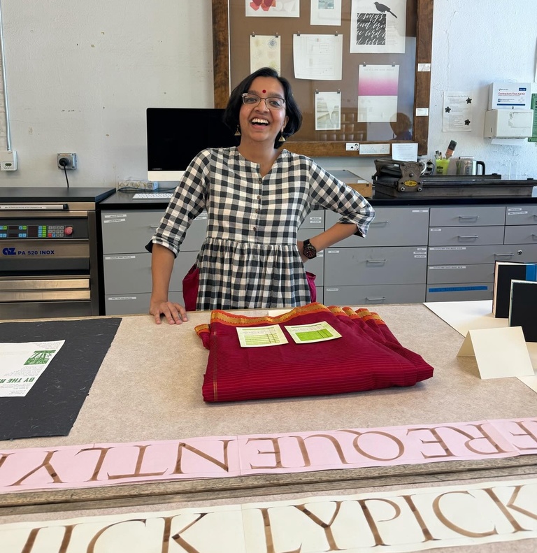 Smiling woman standing behind a table arranged with printed work