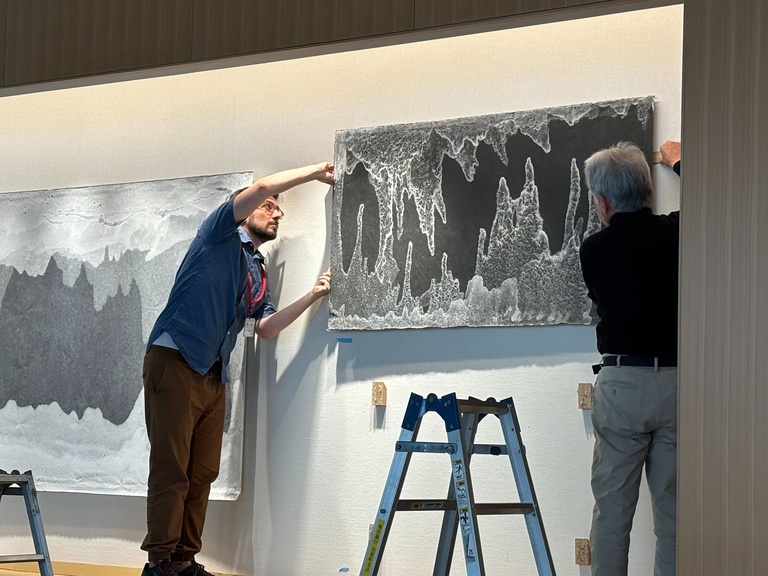 two people installing handmade paper on wall