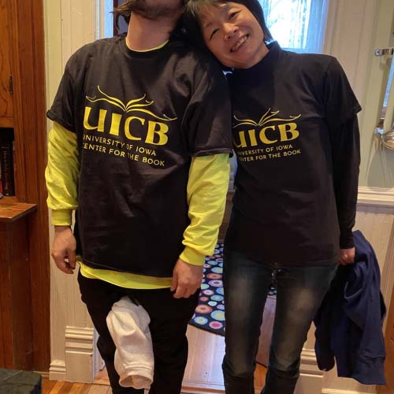 Two Japanese Papermakers wearing UICB shirts stand together looking exhausted