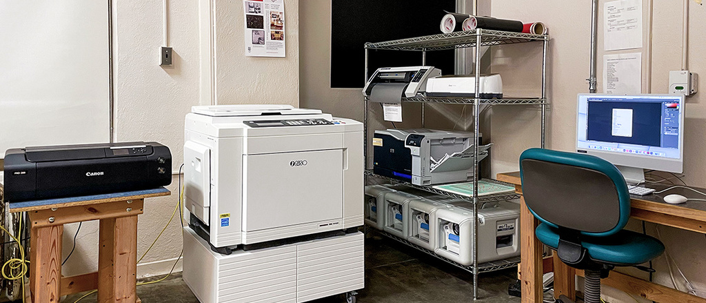 Photo of Risograph, printers, and computers in a room.
