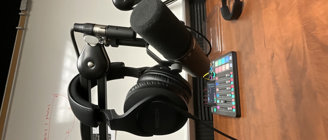 a pair of headphones hanging on a microphone in a recording booth