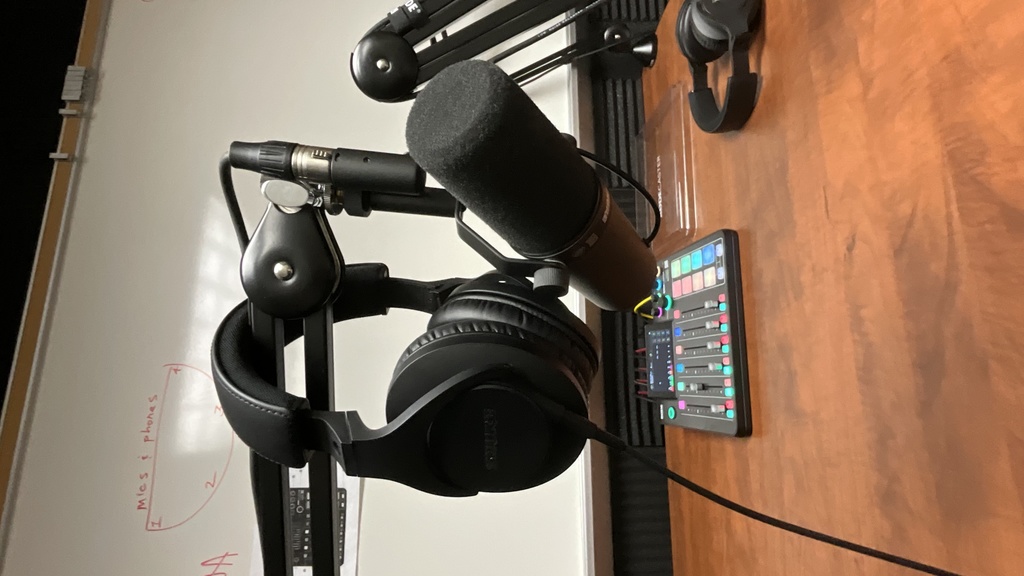 a pair of headphones hanging on a microphone in a recording booth